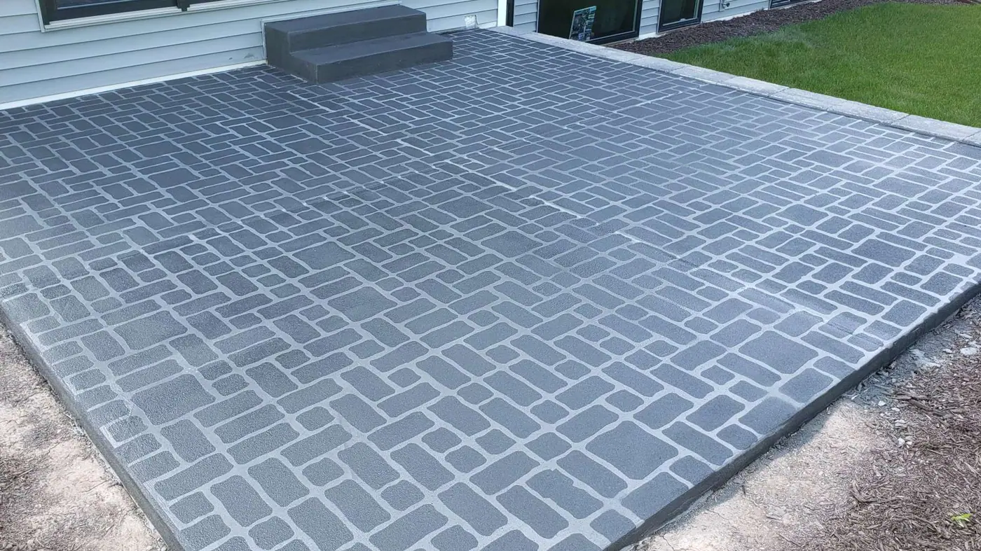 Gray herringbone brick-pattern decorative concrete overlay on a backyard patio